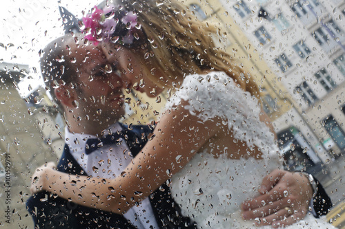 Beautiful bride and groom embracing in rain