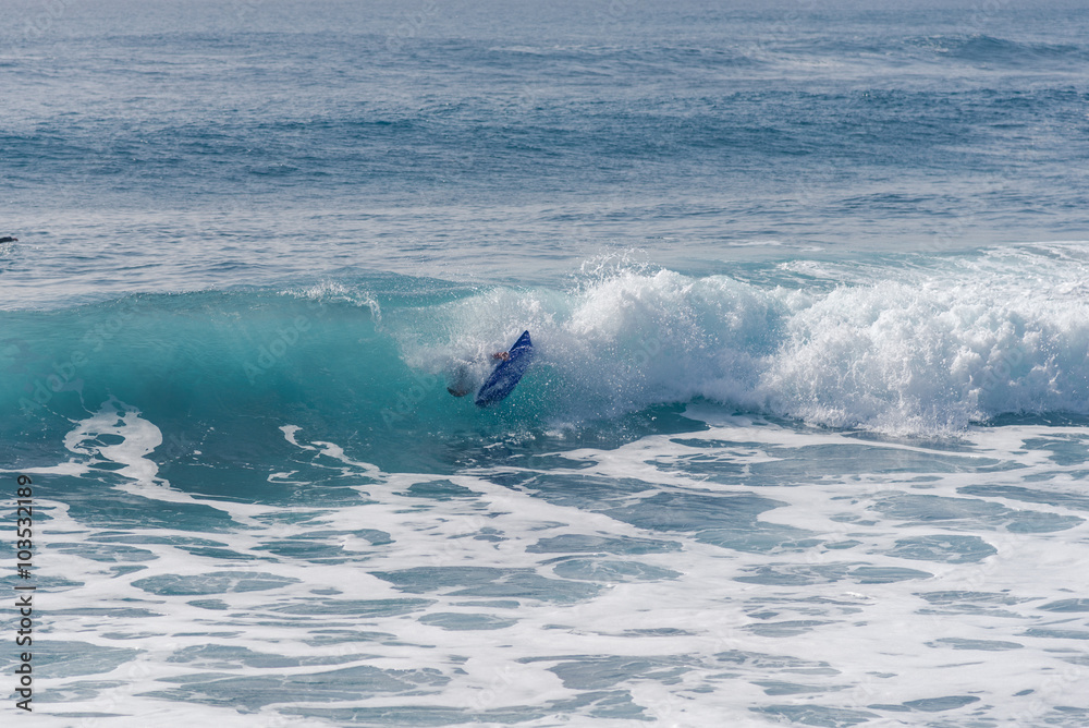 Fototapeta premium Bodyboarding and surfing in the waves of the Atlantic in front of the island La Gomera. A short light type of surfboard ridden in a prone position