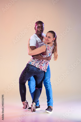 Young couple dances social Caribbean Salsa, studio shot 
