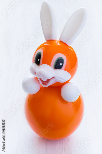 Roly-poly toy rabbit in orange on a white background photo