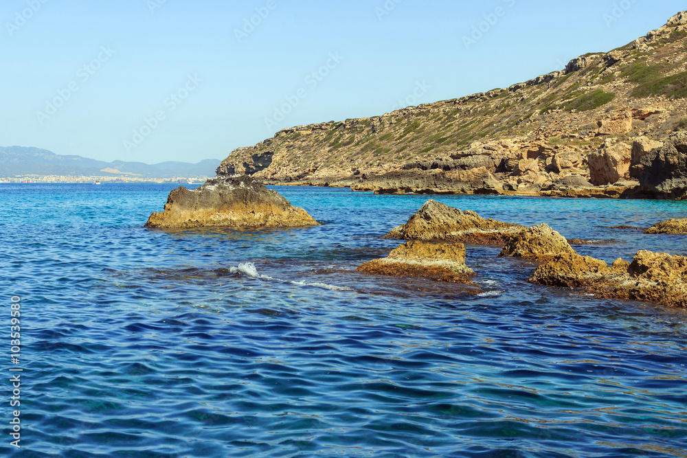 Rocks in the water at  Cap Enderrocat, rocky coastline of Llucmajor, blue and turquoise calm sea, Mallorca, Balearic Islands