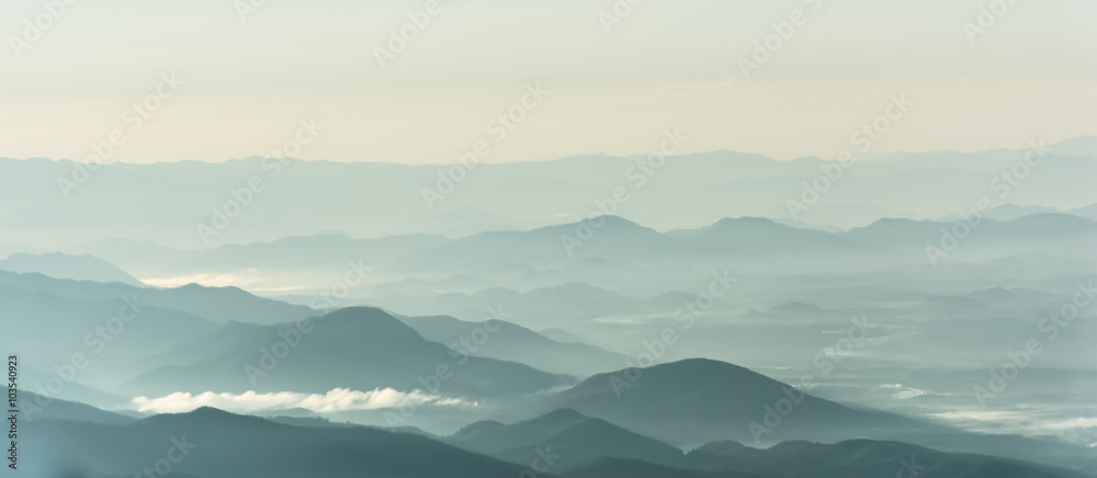 Mountain layer in morning sun ray and winter fog.