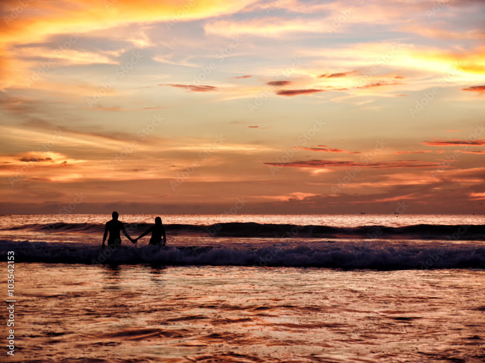 Young couple in the sea against the backdrop of a beautiful suns