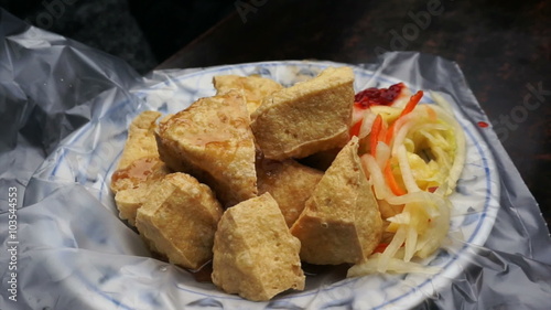 Fried stinky tofu serve on plate with plastic. Famous and iconic fermented tofu of Taiwan photo