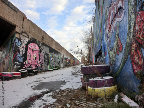 Industrial urban alley with snow and tires and paint - landscape color photo