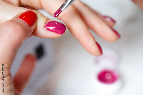 Manicure in process - Beautiful manicured woman s nails with red nail polish. The industry of beauty and nail care  beauty salons  soft focus