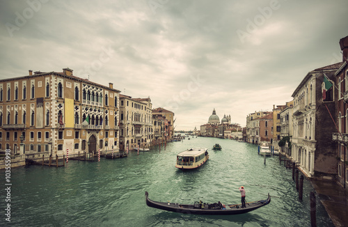 View of traditional Gondola and boats on Canal Grande with Basilica di Santa Maria della Salute church in background at a cloudy day, Venice (Venezia), Italy, Europe, Vintage filtered style 