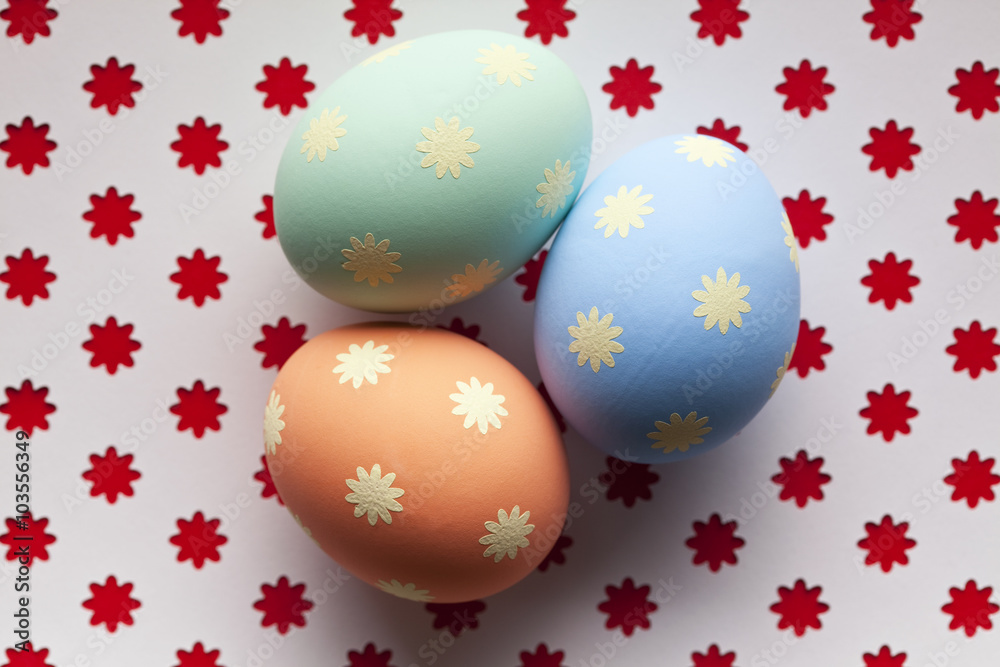 Three colored Easter eggs on patterned background