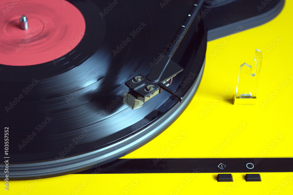 Turntable in yellow case playing a vinyl record with red label ...