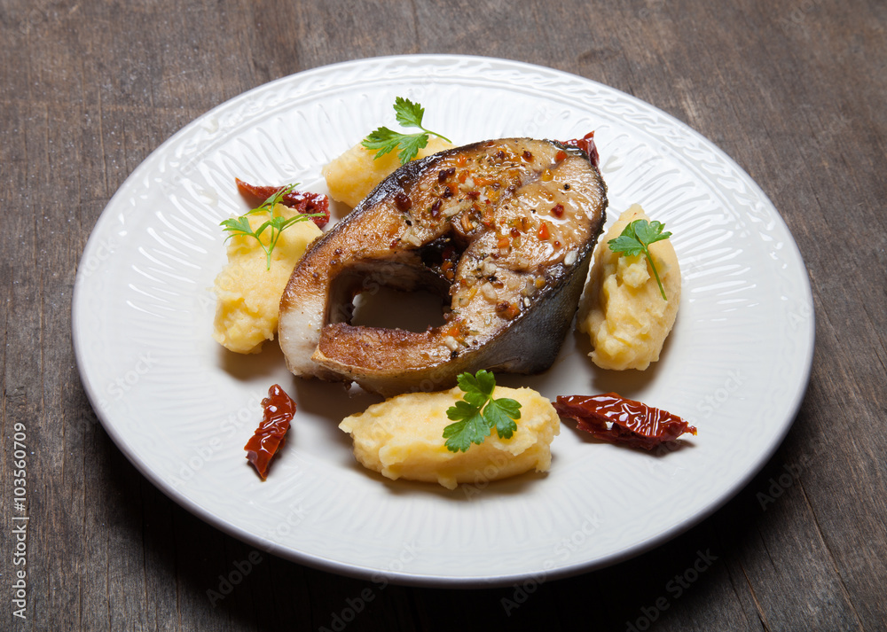 Fried tuna fish with mashed potato, dried tomato and parsley on