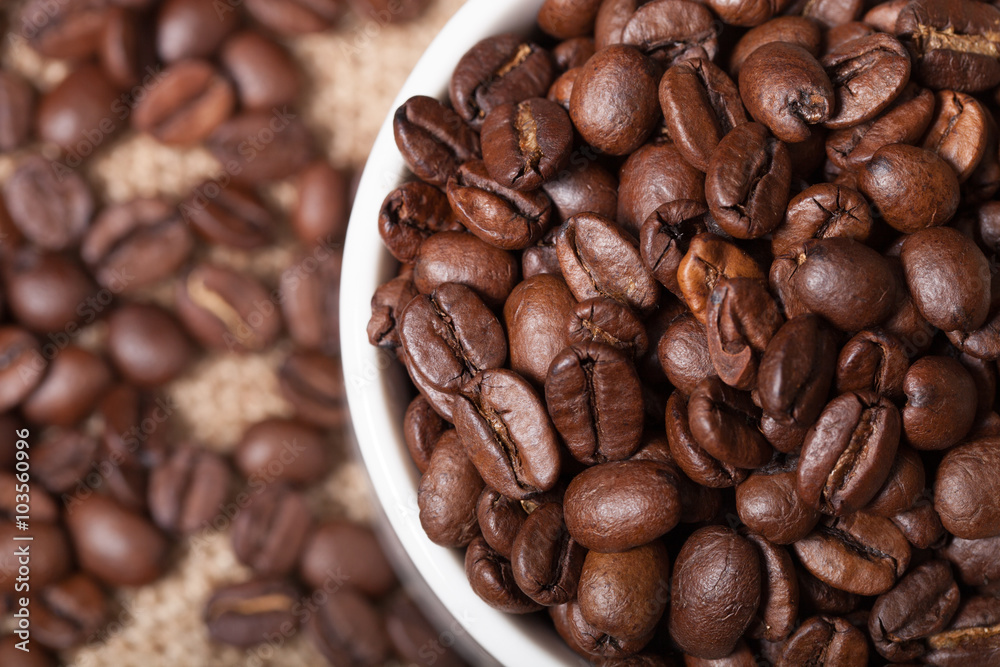 Cup, saucer and coffee beans on a burlap background. Shallow dep Cup, saucer and coffee beans on a burlap background. Shallow dep