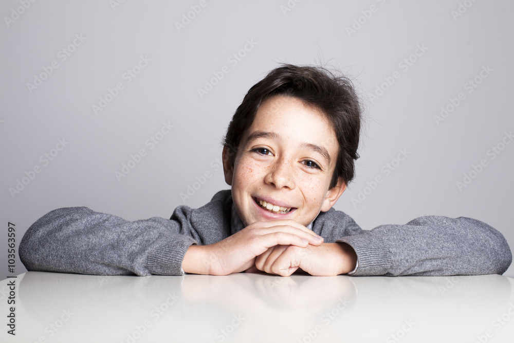Niño sonriendo apoyado sobre la mesa Niño sonriendo apoyado sobre la mesa