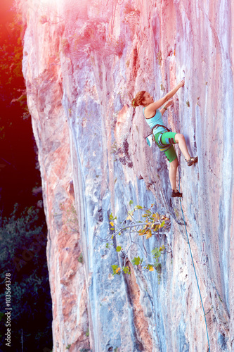 Young Rock Climber ascending steep colorful rocky Wall Lead Climbing