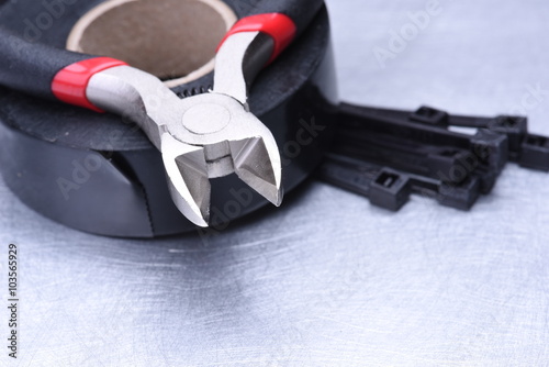 Pliers and electrical accessories on metal surface