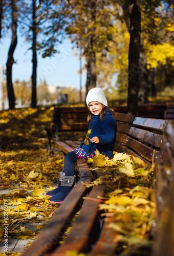 Little girl sitting on a bench in the park