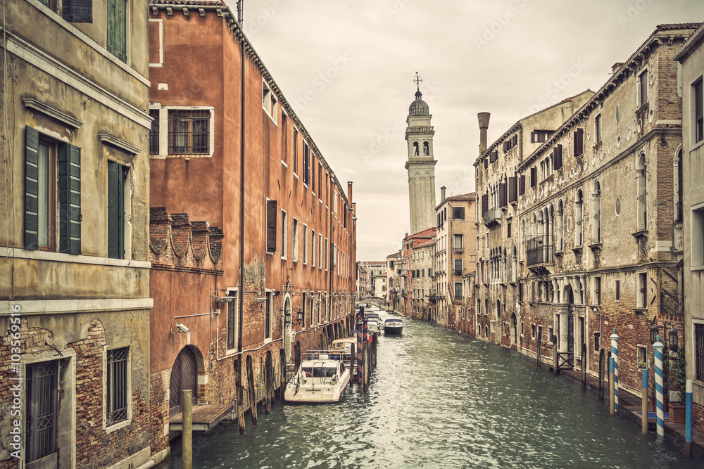 Canal in Venice (Venezia) with old buildings, boats and the leaning belfry tower of San Giorgio dei Greci, Italy, Europe, vintage filtered style
