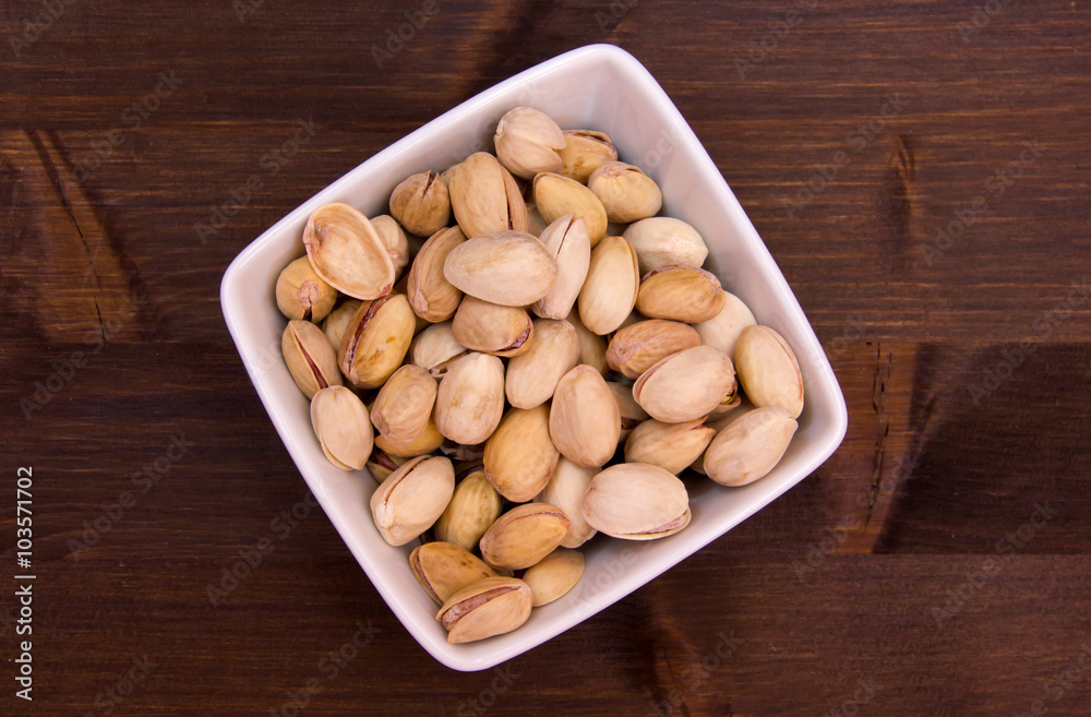 Pistachios on a square bowl on wooden table seen from above Pistachios on a square bowl on wooden table seen from above