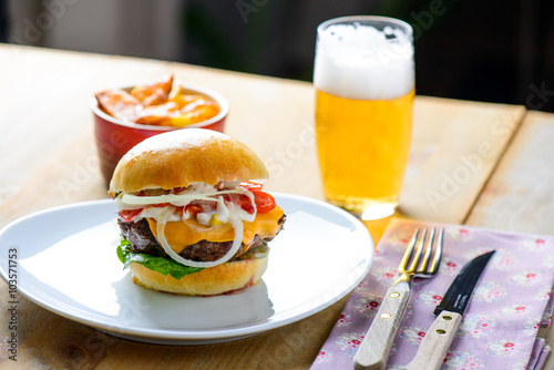 Hamburger with beer and fries in the background ready to be eate