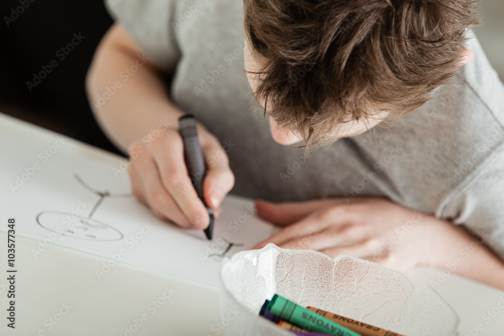 Young Boy Making Artwork Using Crayons at Table Young Boy Making Artwork Using Crayons at Table