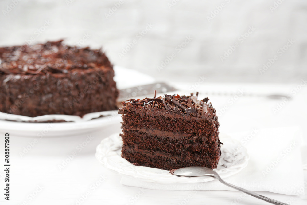 Sliced chocolate cake on wooden table, on light background Sliced chocolate cake on wooden table, on light background