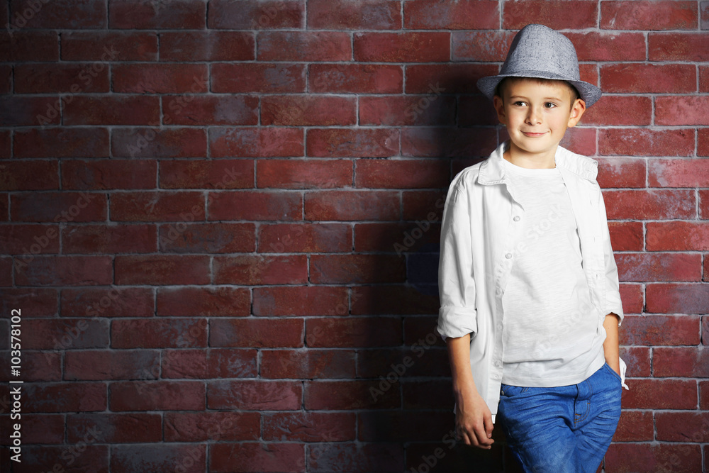 Cute little boy on brick wall background. Kids fashion concept