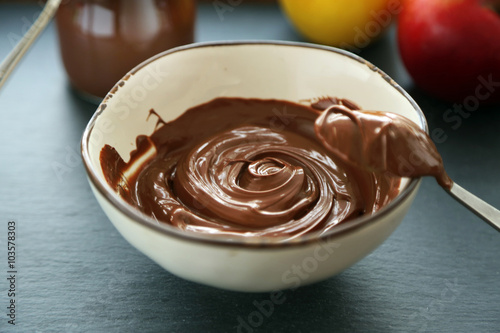 Melted chocolate in bowl, on wooden background