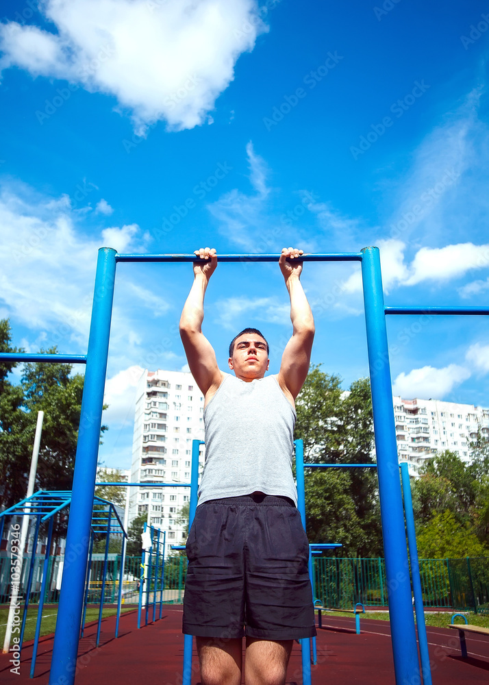 Muscular man doing pull-ups on horizontal bar Muscular man doing pull-ups on horizontal bar