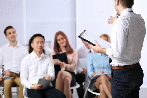 Young businessman standing back and making notes at the office meeting