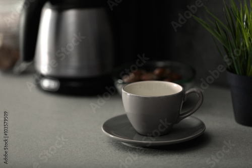 Cup and coffee machine on the kitchen table, close up