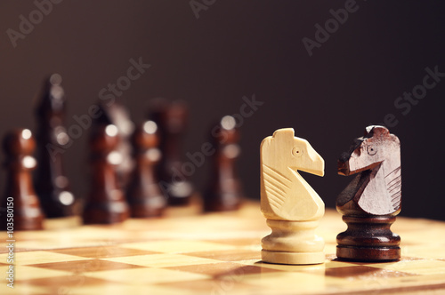 Chess pieces and game board on brown blurred background