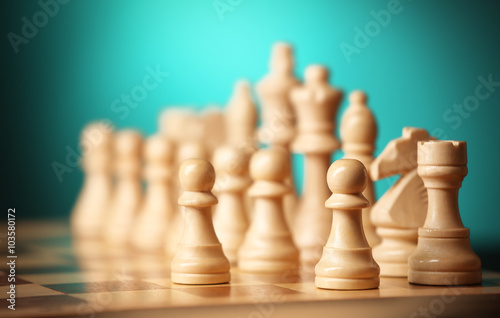 Chess pieces and game board on light green background