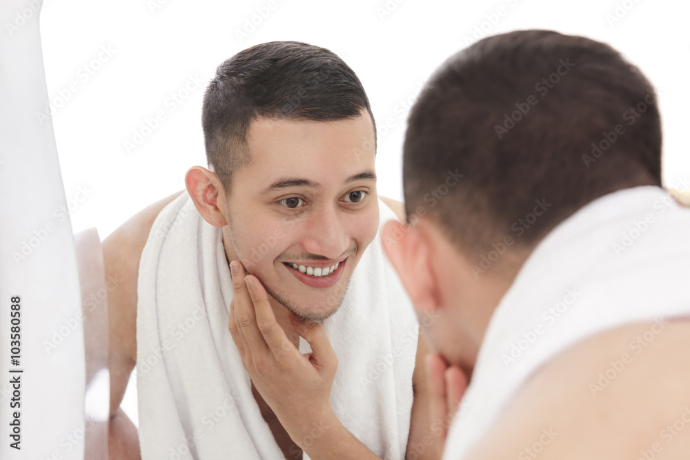 handsome man looking into the mirror and touching his smooth fac handsome man looking into the mirror and touching his smooth fac