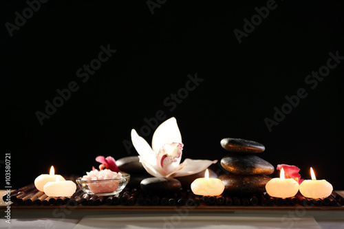 Spa still life with stones  candles and flowers in water on black background