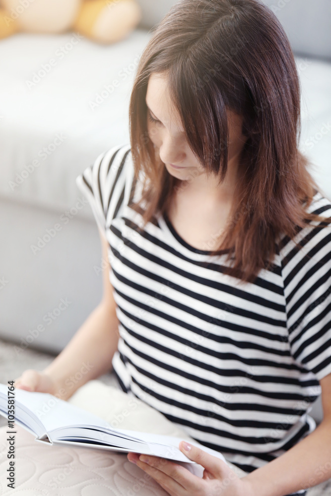 Beautiful girl reading book on carpet, indoor Beautiful girl reading book on carpet, indoor