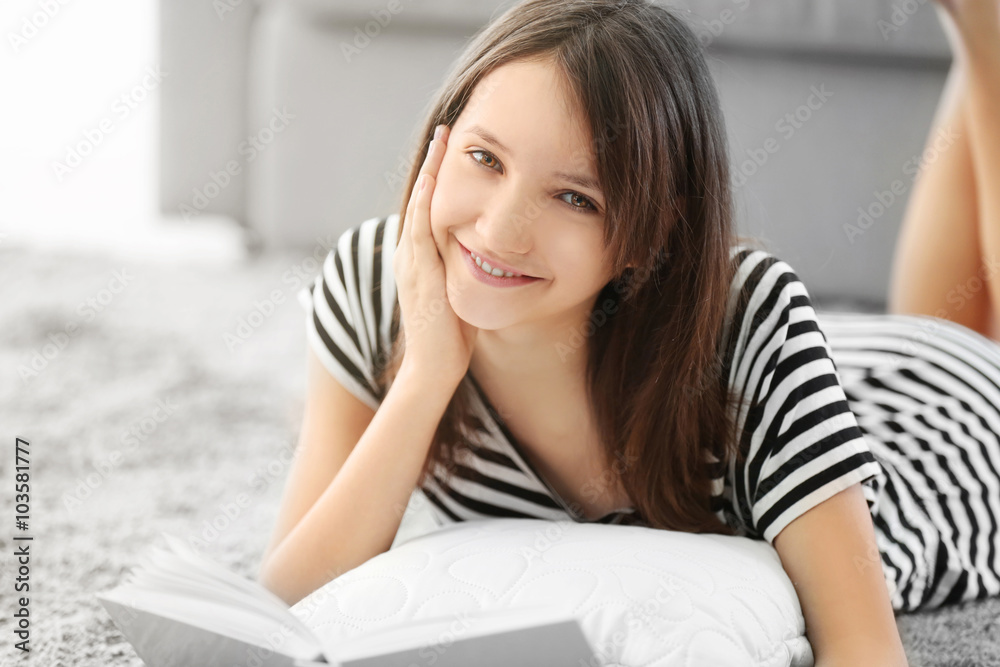Beautiful girl reading book on carpet, indoor Beautiful girl reading book on carpet, indoor