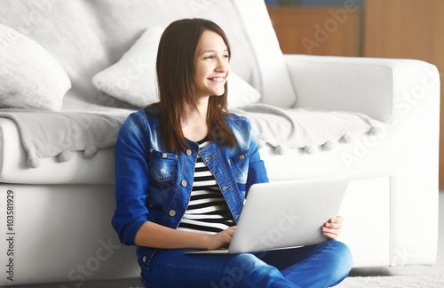 Beautiful girl with laptop on carpet indoor