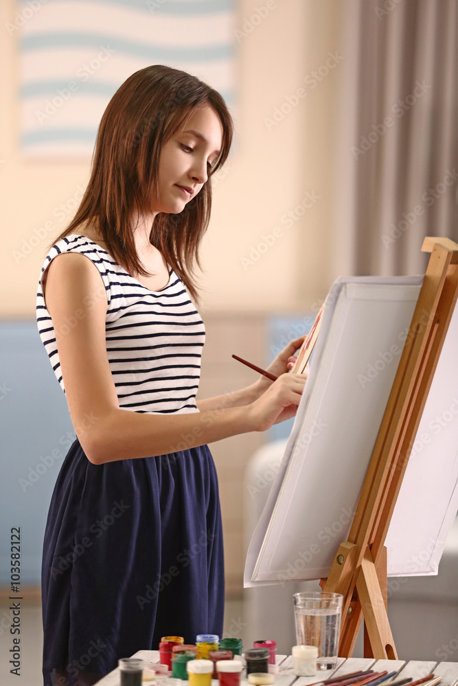 Beautiful girl painting on canvas in room Beautiful girl painting on canvas in room