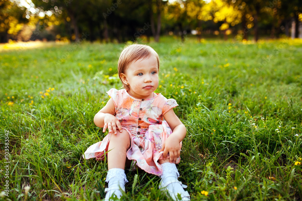 Little girl sitting on the grass.
