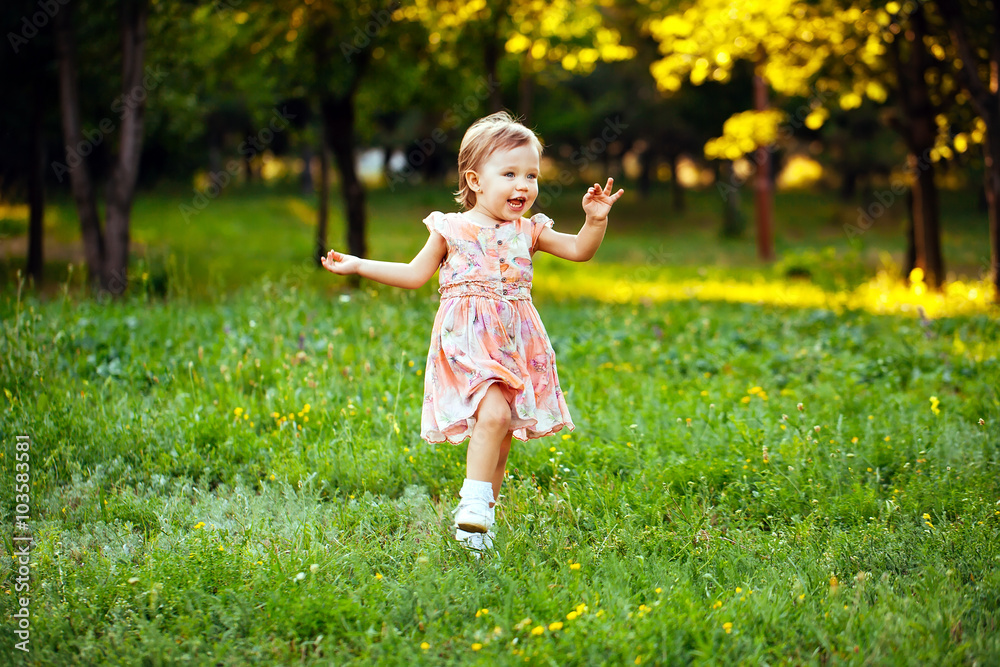 Happy cute little girl running on the grass in the park. Happine Happy cute little girl running on the grass in the park. Happine
