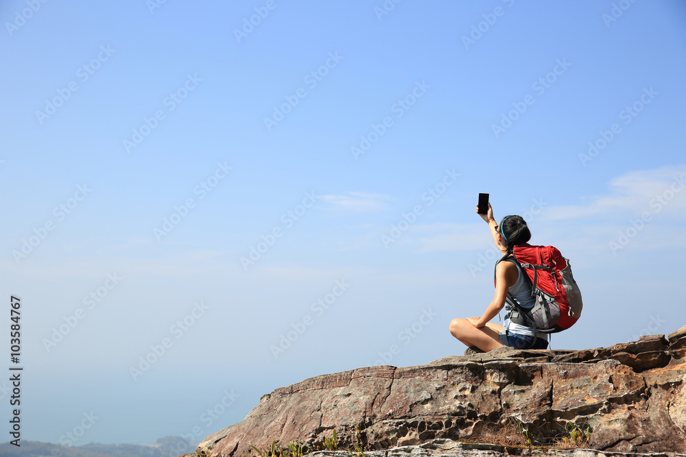 young woman backpacker taking photo with cellphone on mountain peak young woman backpacker taking photo with cellphone on mountain peak