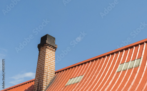 Chimney with roof tiles, Orange on blue sky background