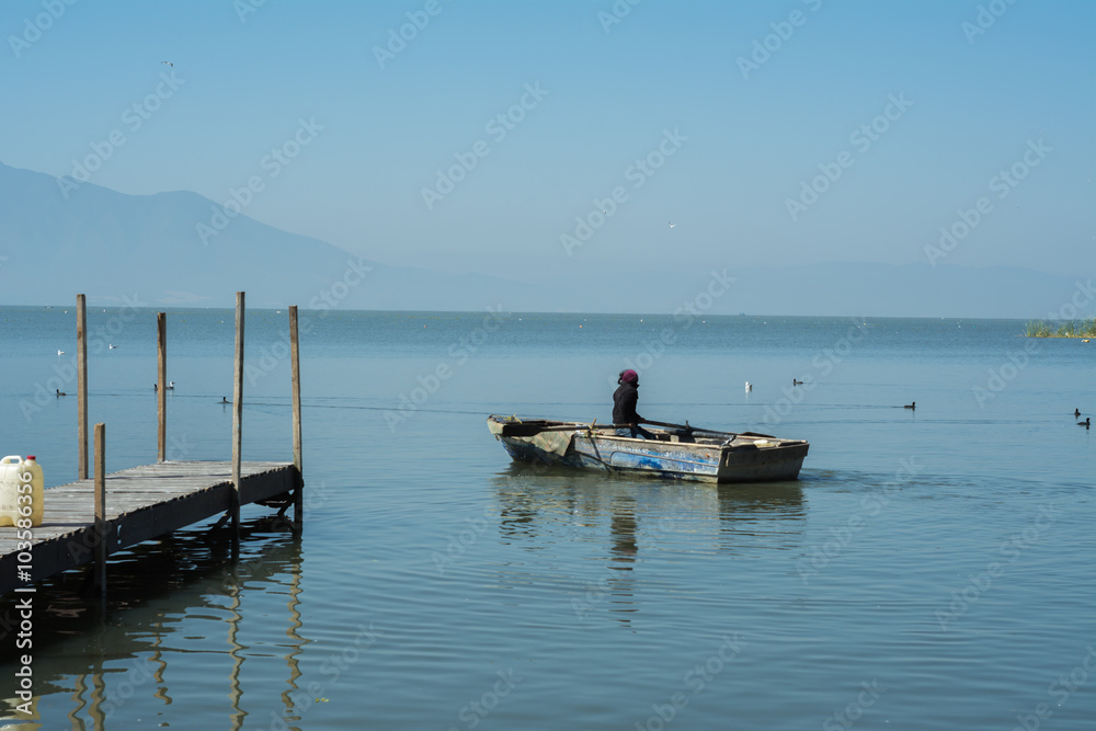 Una niña navega con su lancha cerca del muelle.