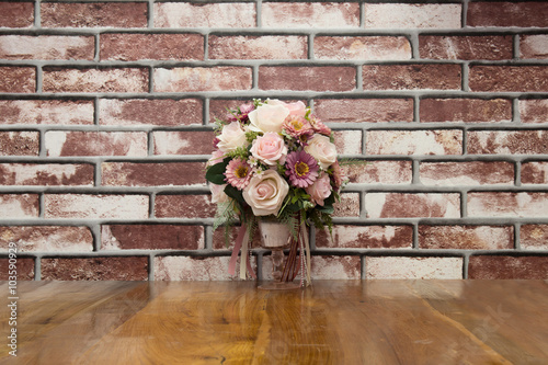 Artificial flowers put on terrace wood with brick wall in vintag photo
