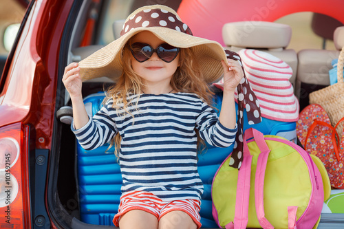 Portrait of a little girl sitting in the trunk of a car photo