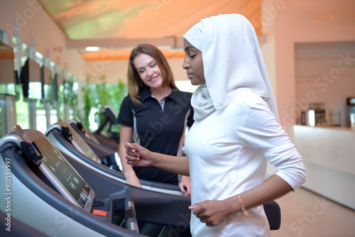 Young arab muslim woman wroking out in a Gym with a trainer