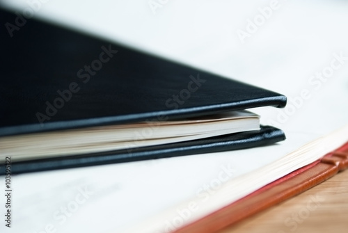 Black leather notebook lies on an open notebook with white sheet