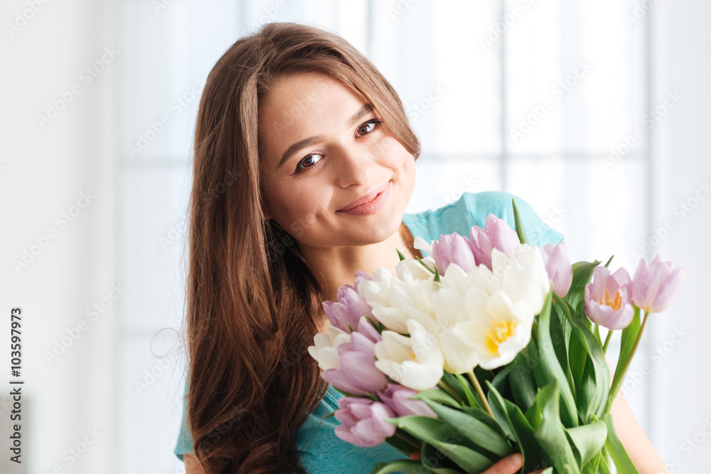 Pretty cheerful young woman with bouquet of flowers