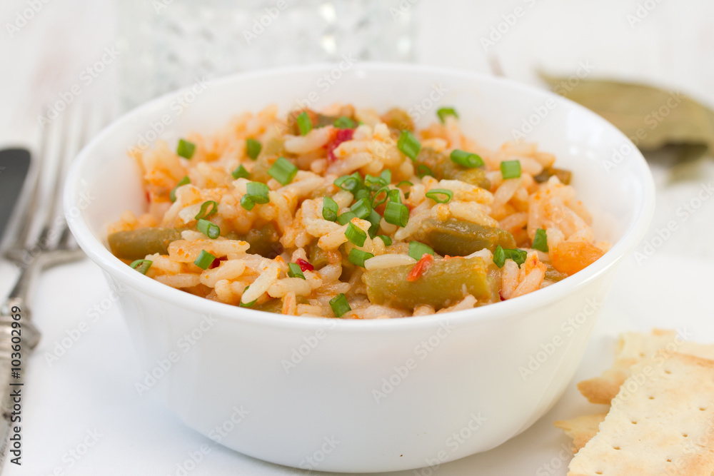 rice with vegetables in white bowl and glass of water