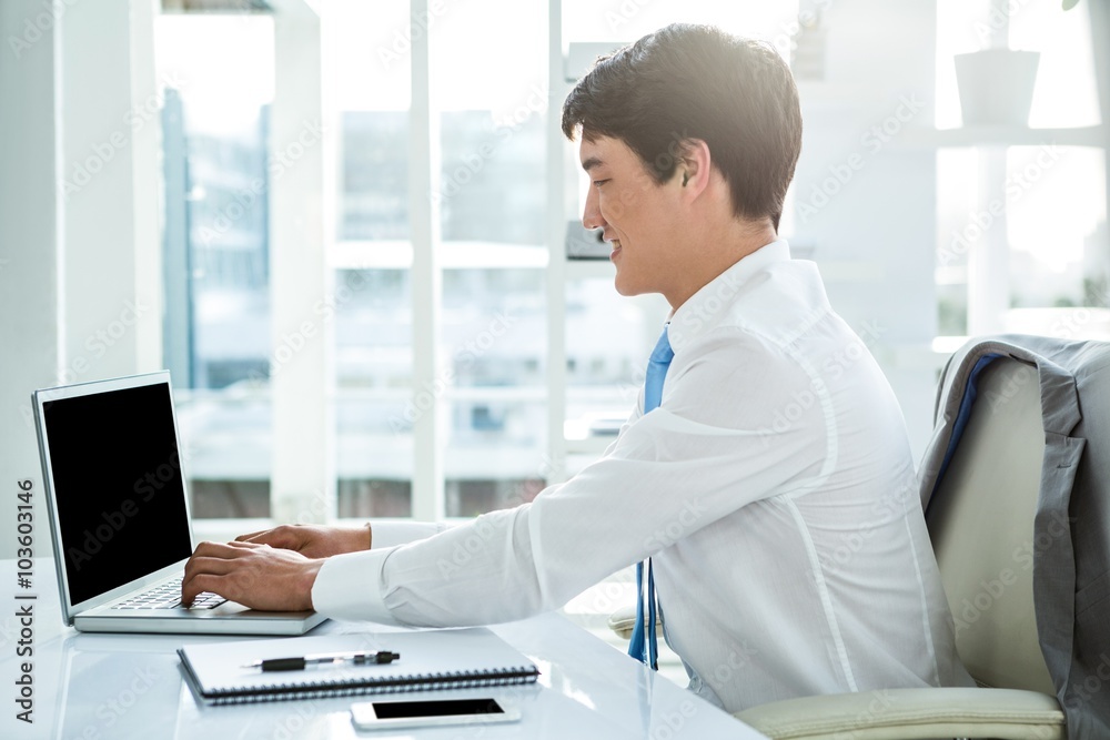 Smiling asian businessman working on laptop Smiling asian businessman working on laptop