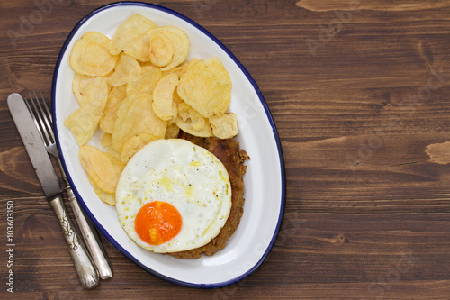 typical portuguese sausage alheira with fried egg and potato on dish on brown background